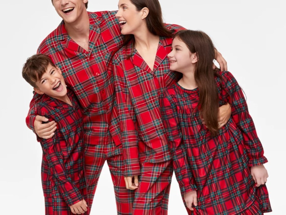 mom, dad, and kids wearing matching red plaid print Christmas pajamas