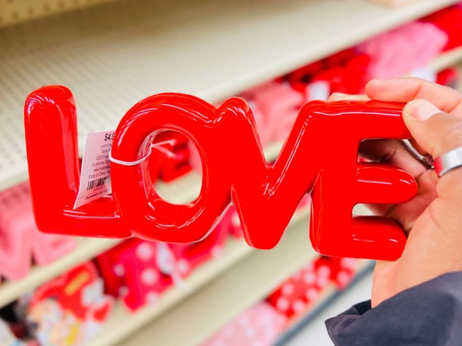 A person holding a LOVE table decor sign