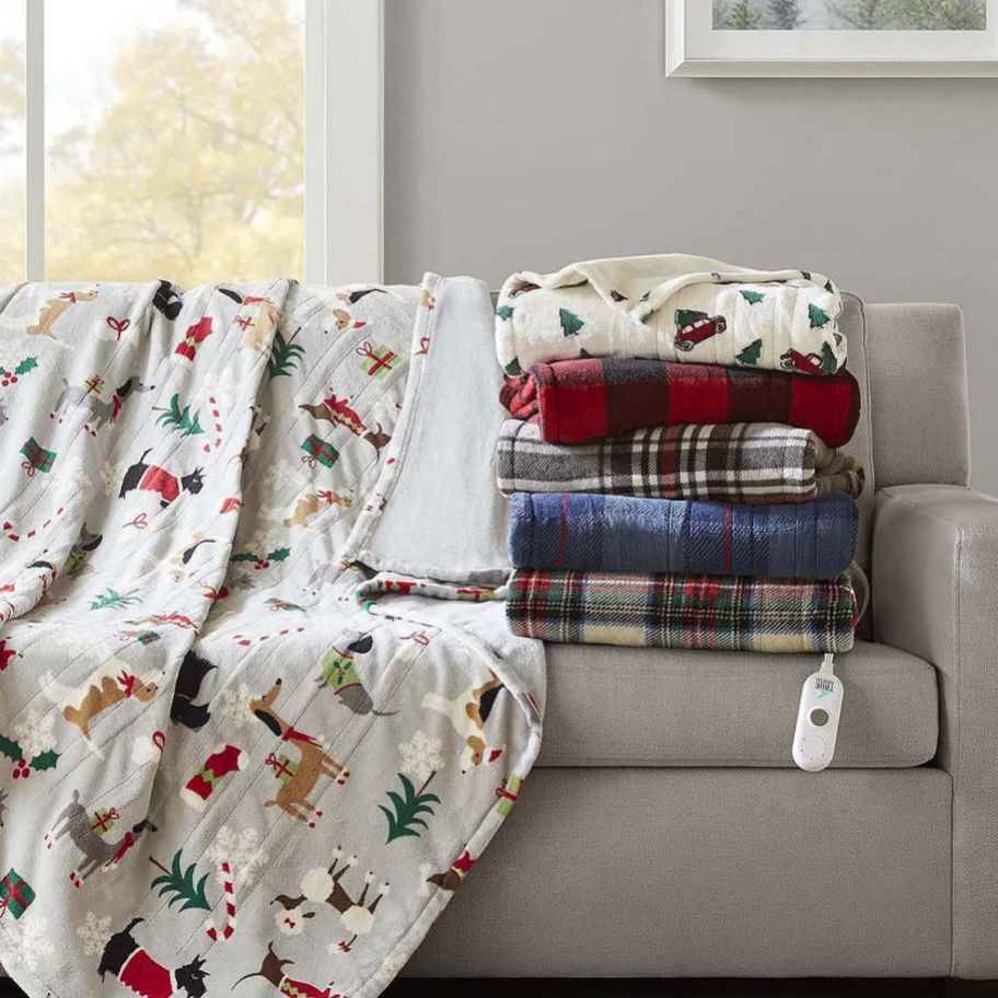 a stack of heated holiday themed throws on a sofa