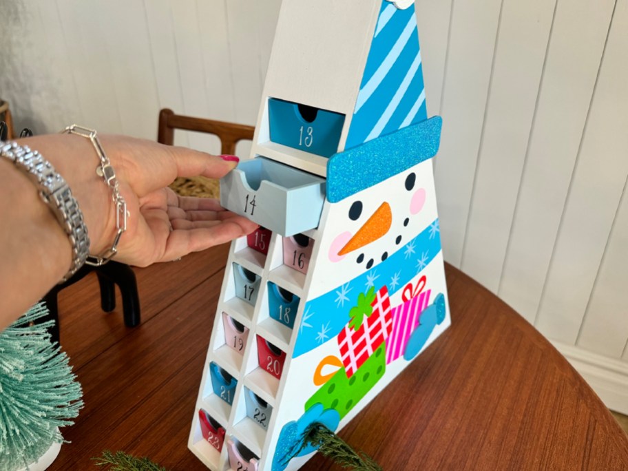 hand taking box out of wooden advent calendar on table