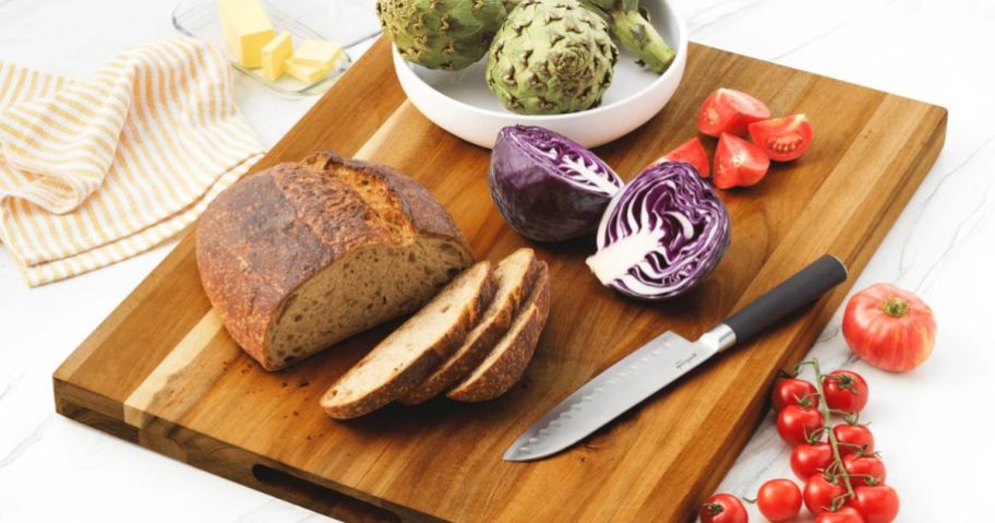 A cutting board with bread and veggies on it