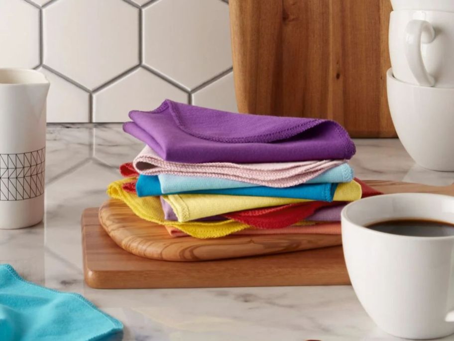 multi color dishcloths stacked on cutting board