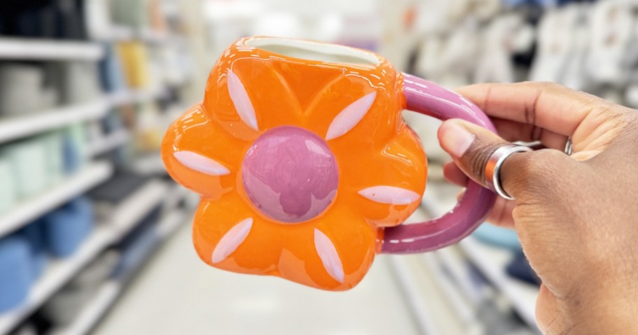 hand holding up and orange and purple flower shaped mug