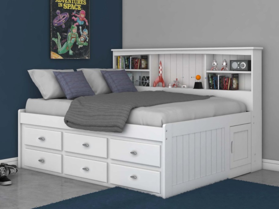 a white twin bed with drawers on the bottom and a bookshelf on the back