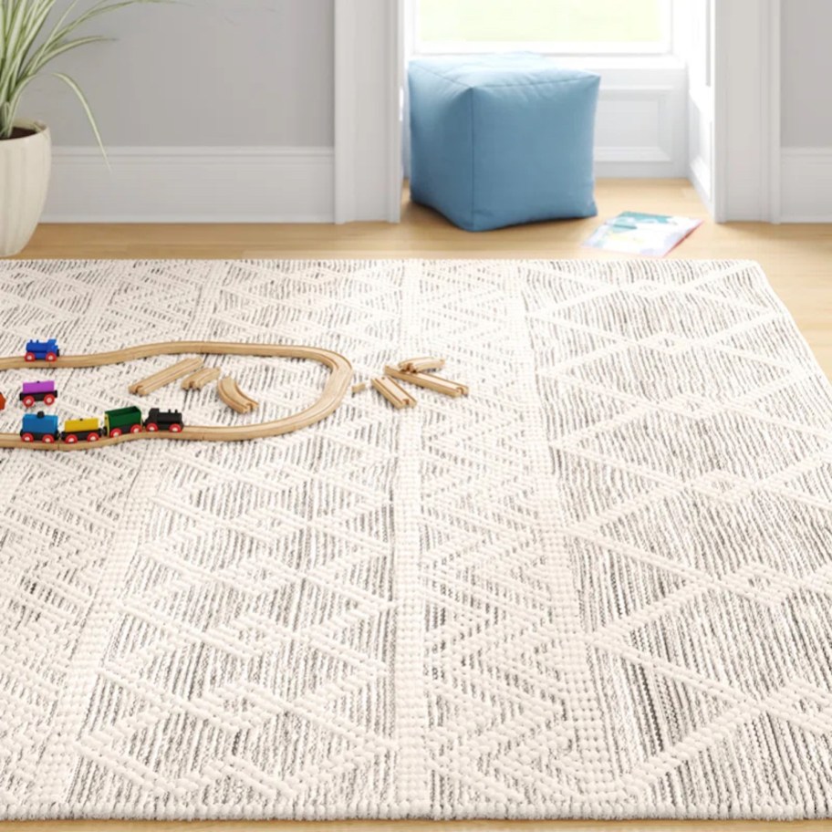 a woman sitting on a grey and cream wool area rug